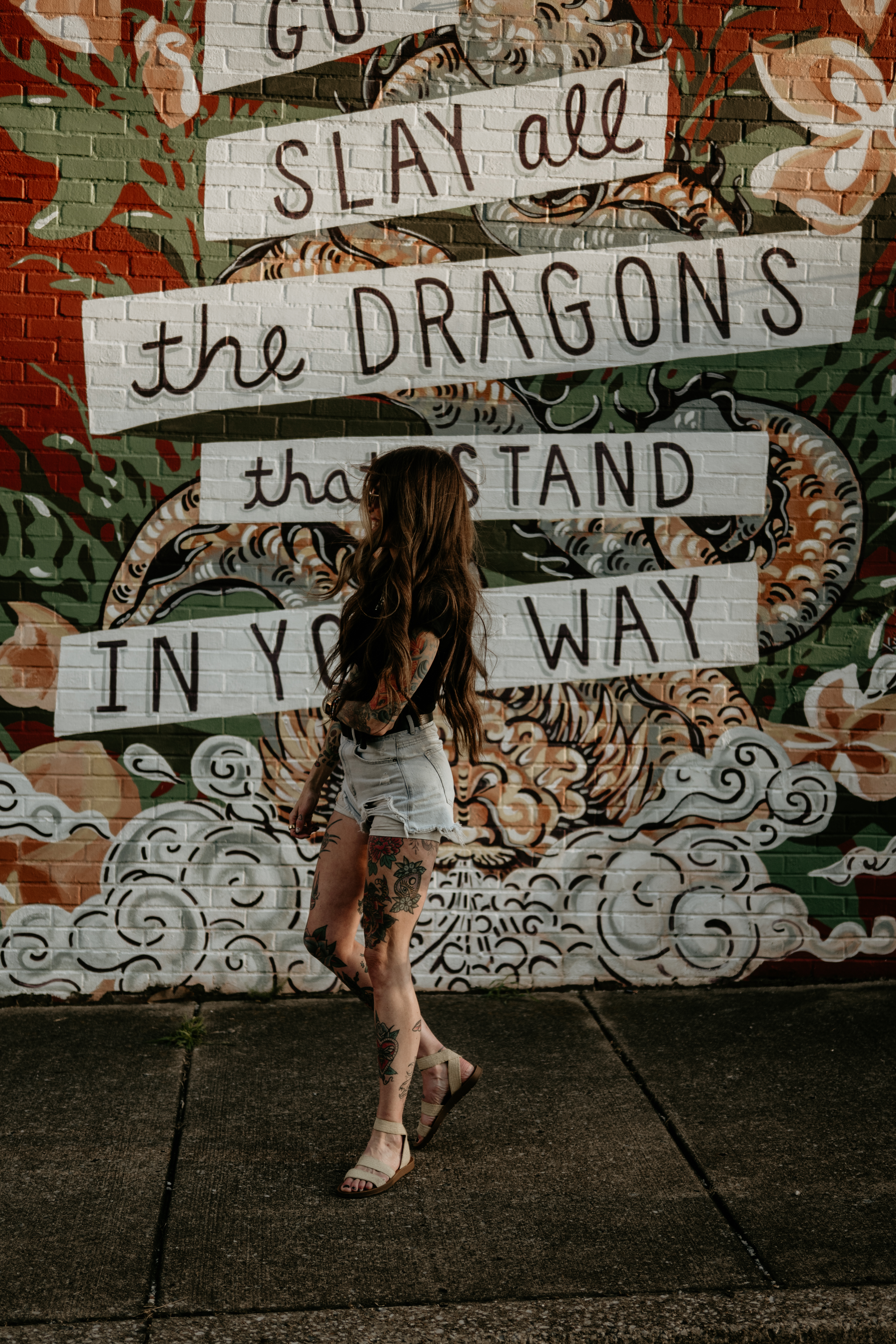 Meg LaForge standing in front of a colorful dragon mural